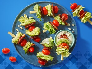 Iceberg lettuce, cherry tomatoes, bacon and salad dressing on skewers. Served alongside aplatter of grilled corn.