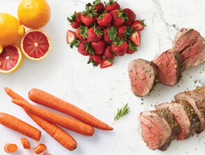 Arrangement of carrots, steak, strawberries, and grapefruit